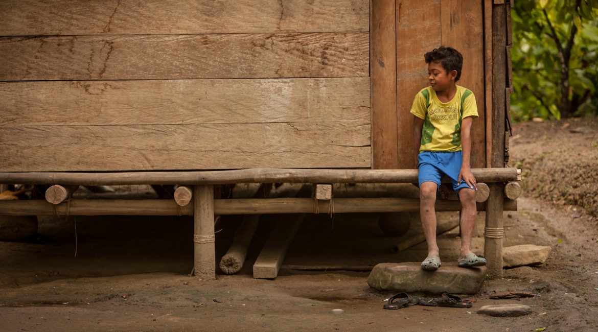 boy sitting on porch of wood house